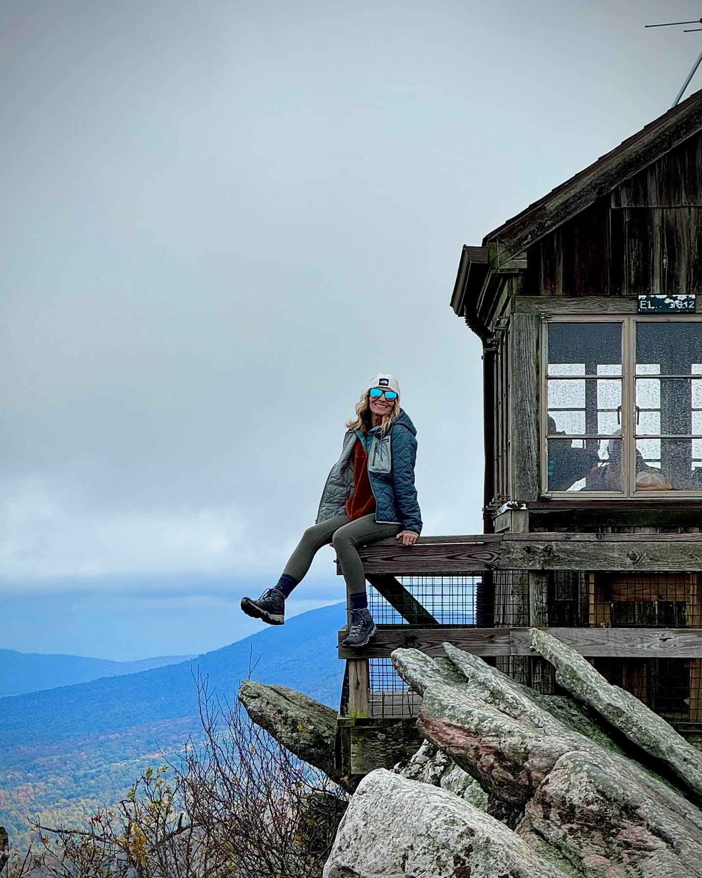 Nicole sitting on the porch of a mountain fire tower